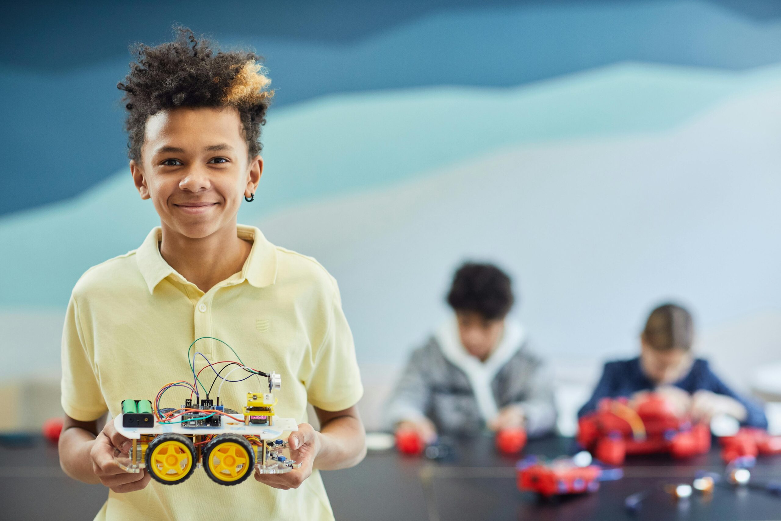 Smiling student holds robotics project during a hands-on STEM activity in the classroom.
